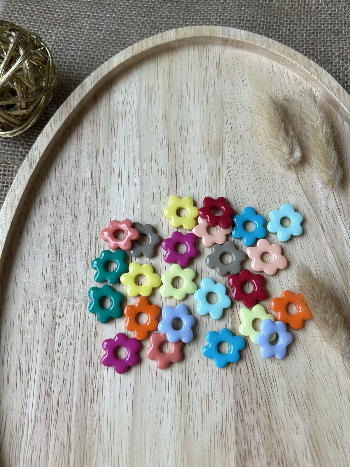 Pampilles en forme de fleurs multicolores de la gamme Noah pour boucles d'oreilles interchangeables Nohulé Création sur un plateau en bois.
