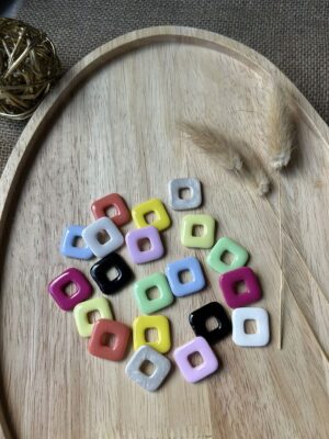 Pampilles carrées multicolores de la gamme Charly pour boucles d'oreilles interchangeables Nohulé Création sur un plateau en bois.