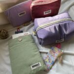 Ensemble d'accessoires artisanaux en velours côtelé Nohulé Création : trousses de maquillage parme et brique, grande trousse de toilette lilas et pochette à livre verte avec marque-page fleuri.
