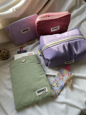 Ensemble d'accessoires artisanaux en velours côtelé Nohulé Création : trousses de maquillage parme et brique, grande trousse de toilette lilas et pochette à livre verte avec marque-page fleuri.