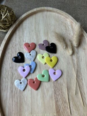 Pampilles en forme de cœurs multicolores de la gamme Nina pour boucles d'oreilles interchangeables Nohulé Création sur un plateau en bois.