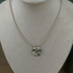 Collier ras de cou avec fil de couleur beige gris et pendentif anneau artisanal Nohulé Création présenté sur un buste d'exposition blanc.