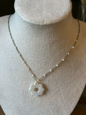 Collier avec chaîne dorée et pendentif en forme de fleur blanc nacré Nohulé Création présenté sur un buste d'exposition blanc.
