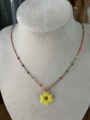 Collier avec chaîne dorée multico et pendentif en forme de fleur jaune Nohulé Création présenté sur un buste d'exposition blanc.